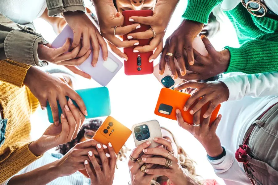 young people standing in circle looking at their phones
